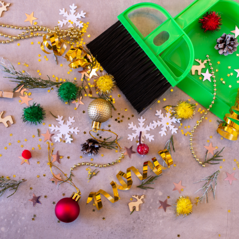 broom and dustpan amid holiday tinsel and ornaments on the floor