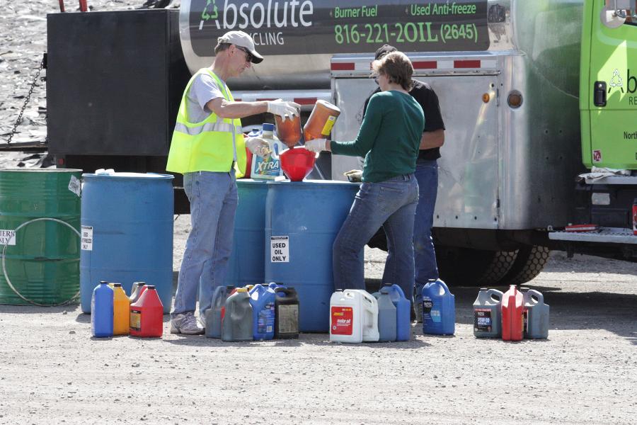 People pouring bottles of household hazardous waste into a barrel for safe disposal