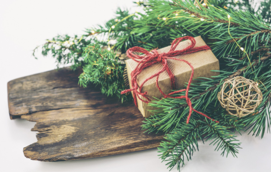 Wrapped package with twine ribbon on top of a an arrangement with pine and wood